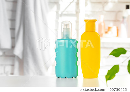 Cosmetic bottles against white bathroom wall background Cosmetic bottles against white bathroom wall background 90730423