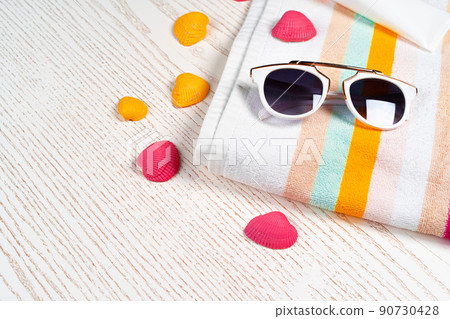 Colorful striped towel with sunglasses and seashells on wooden board Colorful striped towel with sunglasses and seashells on wooden board 90730428
