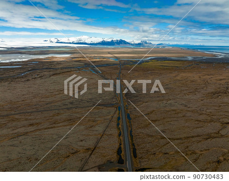 Endless road into the cloudy mountains and hills of Iceland during sunny cloudy weather. Endless road into the cloudy mountains and hills of Iceland during sunny cloudy weather. 90730483