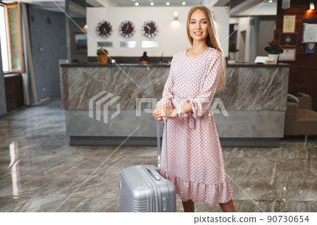 Young attractive woman with packed suitcase standing in hotel lobby Young attractive woman with packed suitcase standing in hotel lobby 90730654