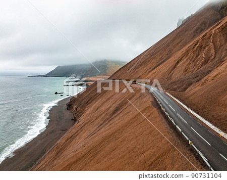 Endless road into the cloudy mountains and hills of Iceland during sunny cloudy weather. 90731104
