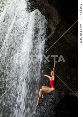 Woman sit on rock under waterfall in tropical jungle Woman sit on rock under waterfall in tropical jungle 90731305