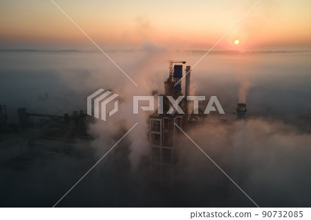 Aerial view of cement factory with high concrete plant structure and tower crane at industrial production site on foggy morning. Manufacture and global industry concept. Aerial view of cement factory with high concrete plant structure and tower crane at industrial production site on foggy morning. Manufacture and global industry concept. 90732085