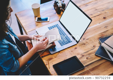 Unrecognizable freelancer with textbook using blank netbook with copy space area 90732259