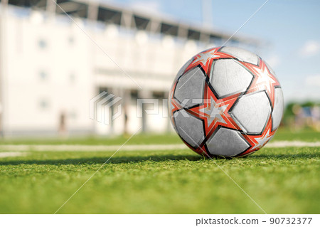 Soccer ball with red stars on the green artificial grass of the football field in the stadium. Summer sunny day. Youth Sports soccer School. Background with copy space 90732377