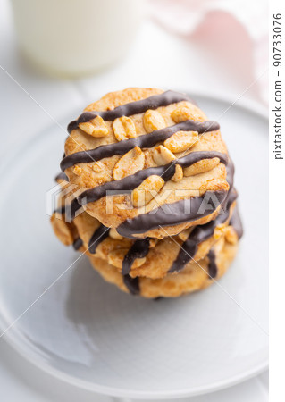 Chip cookies with peanuts and chocolate strips on white table. Chip cookies with peanuts and chocolate strips on white table. 90733076