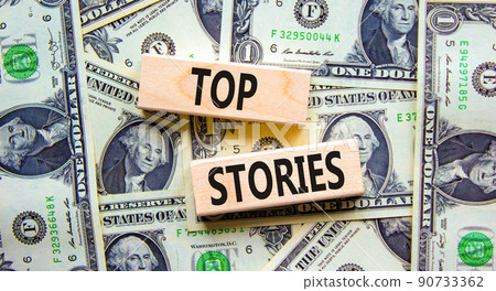 Top stories symbol. Concept words Top stories on wooden blocks on a beautiful background from dollar bills. Business story and top stories concept, copy space. Top stories symbol. Concept words Top stories on wooden blocks on a beautiful background from dollar bills. Business story and top stories concept, copy space. 90733362