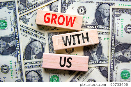 Grow with us symbol. Concept words Grow with us on wooden blocks on a beautiful background from dollar bills. Business, motivational and grow with us concept. Copy space. 90733406