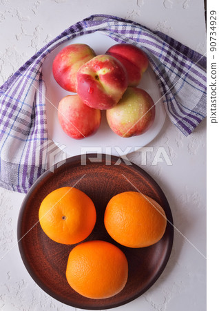 Nectarines and oranges in a plate of fresh fruit. 90734929