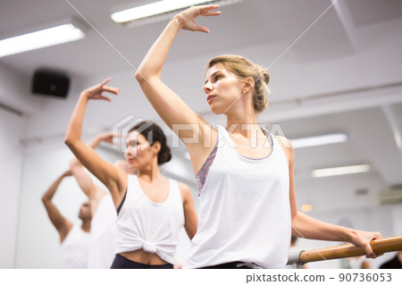 Women in ballet class, holding bar in ballet pose closeup Women in ballet class, holding bar in ballet pose closeup 90736053