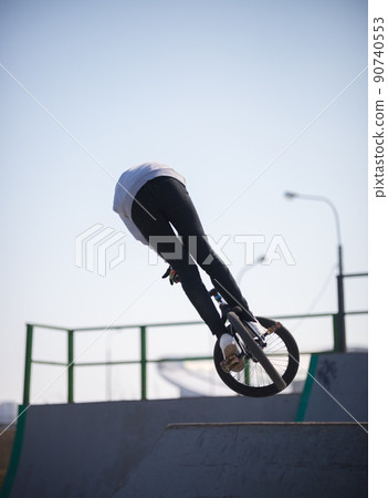 A man on a bicycle on the top of the half pipes training the skill 90740553
