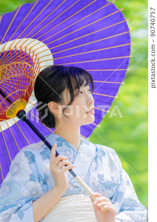 A woman wearing a yukata who walks around the city coolly with a Japanese umbrella 90740757