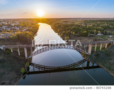 Beautiful view of the arched railway bridge across the Iset River in the city of Kamenkk-Uralsky at sunset in spring. Kamensk-Uralskiy, Sverdlovsk region, Ural mountains, Russia. 90743206