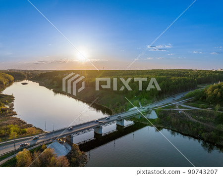 Beautiful view of the bridge across the Iset river in the city of Kamensk-Uralsky at sunset in spring. Kamensk-Uralskiy, Sverdlovsk region, Ural mountains, Russia. Beautiful view of the bridge across the Iset river in the city of Kamensk-Uralsky at sunset in spring. Kamensk-Uralskiy, Sverdlovsk region, Ural mountains, Russia. 90743207