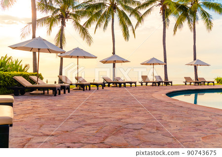 Umbrella and chair around swimming pool in resort hotel for leisure travel and vacation neary sea ocean beach 90743675