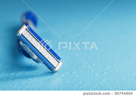 Razor blades on a blue background with drops of icy water 90744984