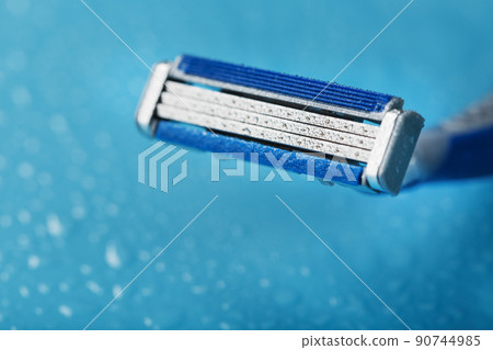 Razor blades on a blue background with drops of icy water 90744985