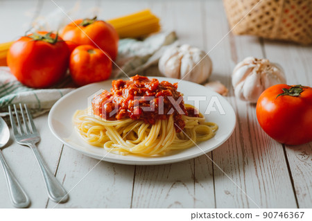 Delicious homemade Spaghetti pasta with tomato sauce and minced meat served on a white plate with ingredient on white wooden background. Italian food. Homemade food. 90746367