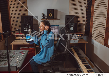 Pleasant radio presenter wearing headphones talking into professional microphone in a broadcasting and recording studio Pleasant radio presenter wearing headphones talking into professional microphone in a broadcasting and recording studio 90746998