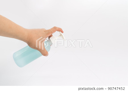 Asian mand hand holds a gel alcohol pump bottle and ready to pushes on it. It's an isolated object on the white clear screen in studio light. 90747452