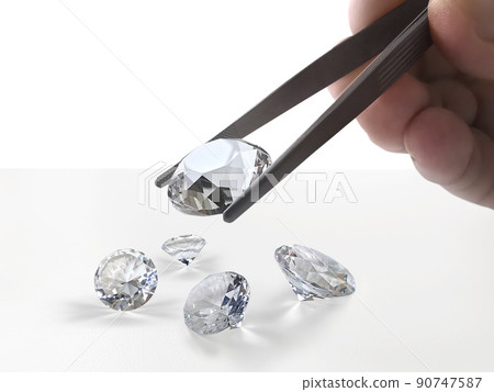 brilliant cut diamond held by tweezers 90747587