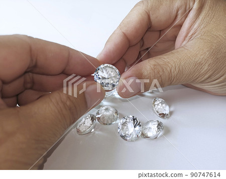 Close-up of the hand of jeweller gemologist with round cut diamonds Close-up of the hand of jeweller gemologist with round cut diamonds 90747614
