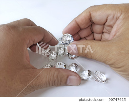 Close-up of the hand of jeweller gemologist with round cut diamonds 90747615