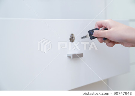women hand holding the black simple key to open the white wardrobe. Clear background. women hand holding the black simple key to open the white wardrobe. Clear background. 90747948