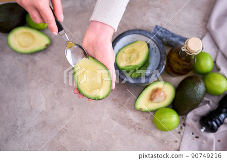 Closeup on hands holding fresh avocado cut in half making guacamole Closeup on hands holding fresh avocado cut in half making guacamole 90749216