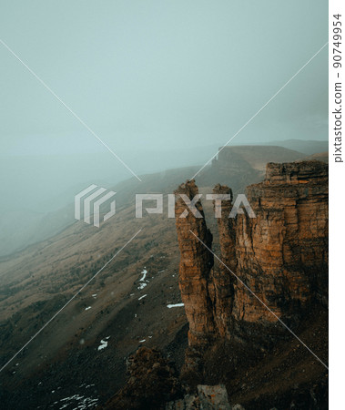 sheer cliffs in a foggy haze from the height of a neighboring peak 90749954