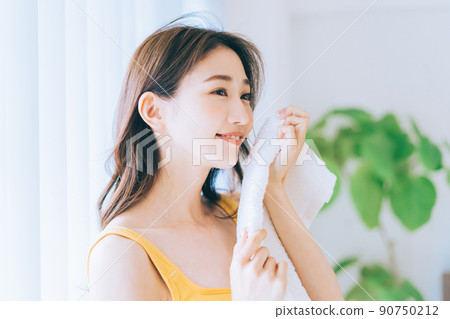 A woman wiping his face with a towel 90750212