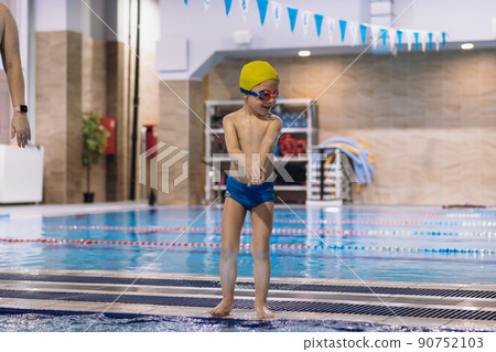 little caucasian boy wearing goggles going to dive into swimming pool 90752103