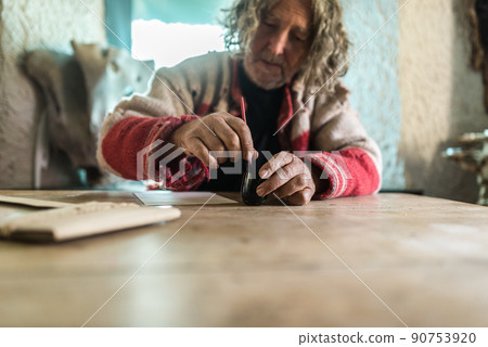 Elderly man using a pot of ink to do calligraphy 90753920