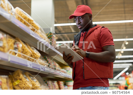 African American male manager of supermarket entering prices of food products 90754564