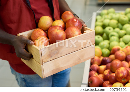 Hands of young black man holding wooden box with fresh ripe red apples Hands of young black man holding wooden box with fresh ripe red apples 90754591