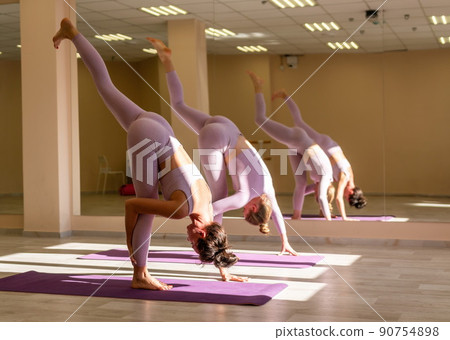 Well looking middle aged sporty woman, fitness instructor in pink sportswear doing stretching and pilates on yoga mat in the studio with mirror. Female fitness yoga. Healthy lifestyle and harmony. 90754898