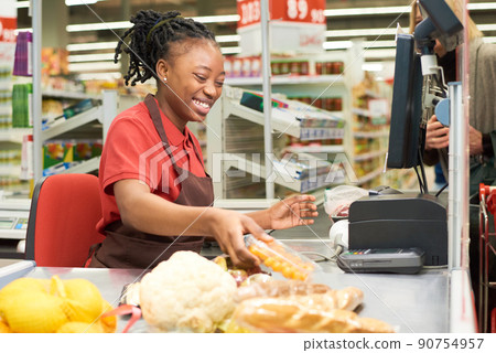 Shop assistant scanning food products and putting them on other side of counter 90754957
