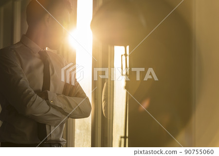 Business man looking through the window at sunset 90755060