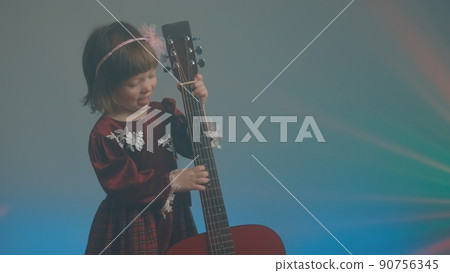 Cute little girl stands on stage in vintage dress and plays an acoustic guitar like a counter bass or cello. The concept of performing the author jazz and blues music. Hobbies and art among children Cute little girl stands on stage in vintage dress and plays an acoustic guitar like a counter bass or cello. The concept of performing the author jazz and blues music. Hobbies and art among children 90756345