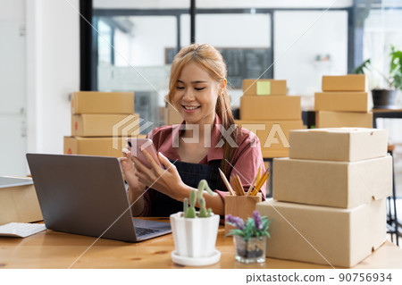 Startup small business entrepreneur SME freelance woman work with mobile phone, Young Asian owner use computer, online market packing box delivery, SME e-commerce telemarketing concept 90756934