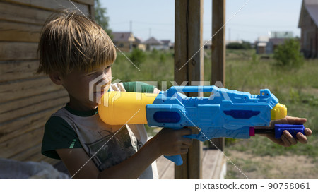 Boy play with water gun toy in garden. Boy play with water gun toy in garden. 90758061