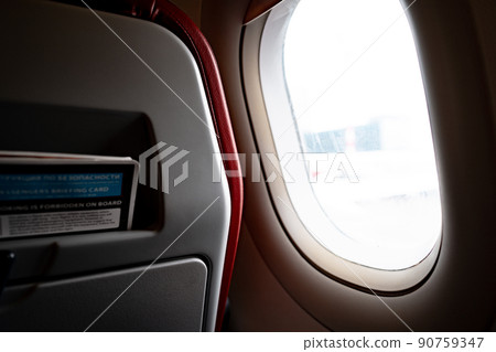 Seats and window inside a dark aircraft 90759347