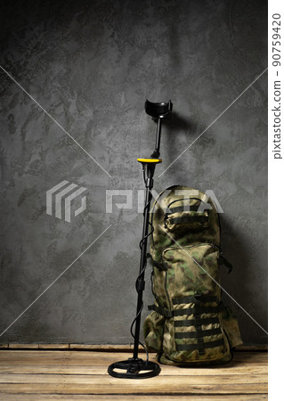 Metal detector and backpack on dark gray background Metal detector and backpack on dark gray background 90759420