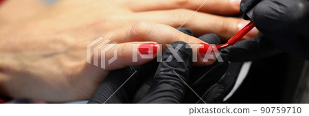 Professional salon worker cover clients nails with red colour polish Professional salon worker cover clients nails with red colour polish 90759710