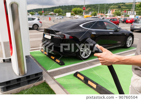 Man holding plug of electric car 90760504