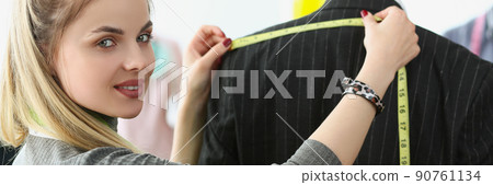 Young woman dressmaker making measurements on mans back for further sewing Young woman dressmaker making measurements on mans back for further sewing 90761134