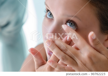 How to put contact lenses: Step by step photo instruction. Step 3: girl pulled back her lower eyelid and brought contact lens to her eye to put. 90762223