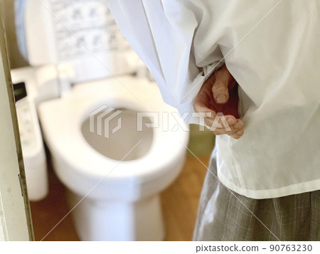 A woman holding her stomach in front of the toilet bowl 90763230