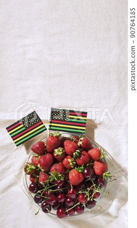 Juneteenth day picnic background with Black Liberation African American flags, sweet salad with cherries and strawberries, strawberry cheesecake 90764185