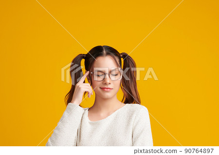 Curious Asian girl is thinking and standing on yellow background with curious face, blank copy space for your advertising content. 90764897